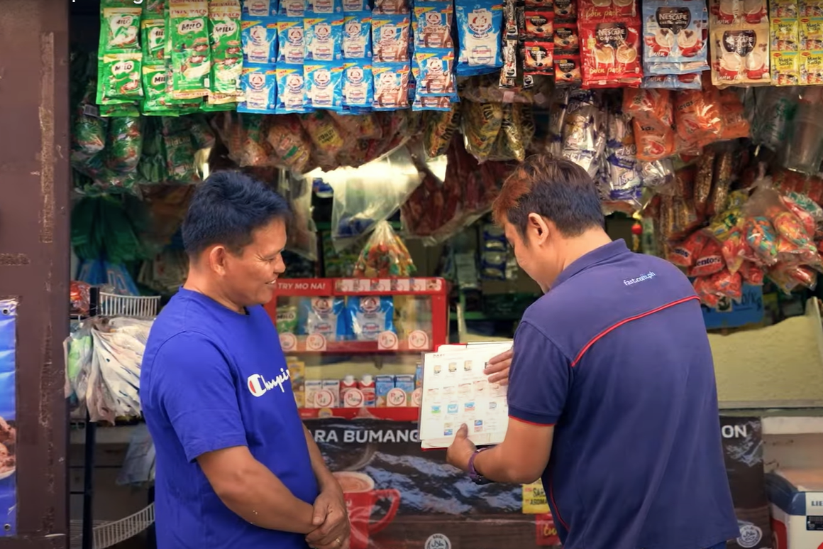 FAST Logistics Group employee offering discounts to a sari-sari store owner